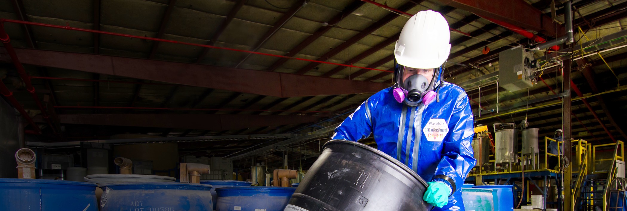 Persona que lleva Lakeland Pyrolon  productos mientras manipula barriles de productos químicos