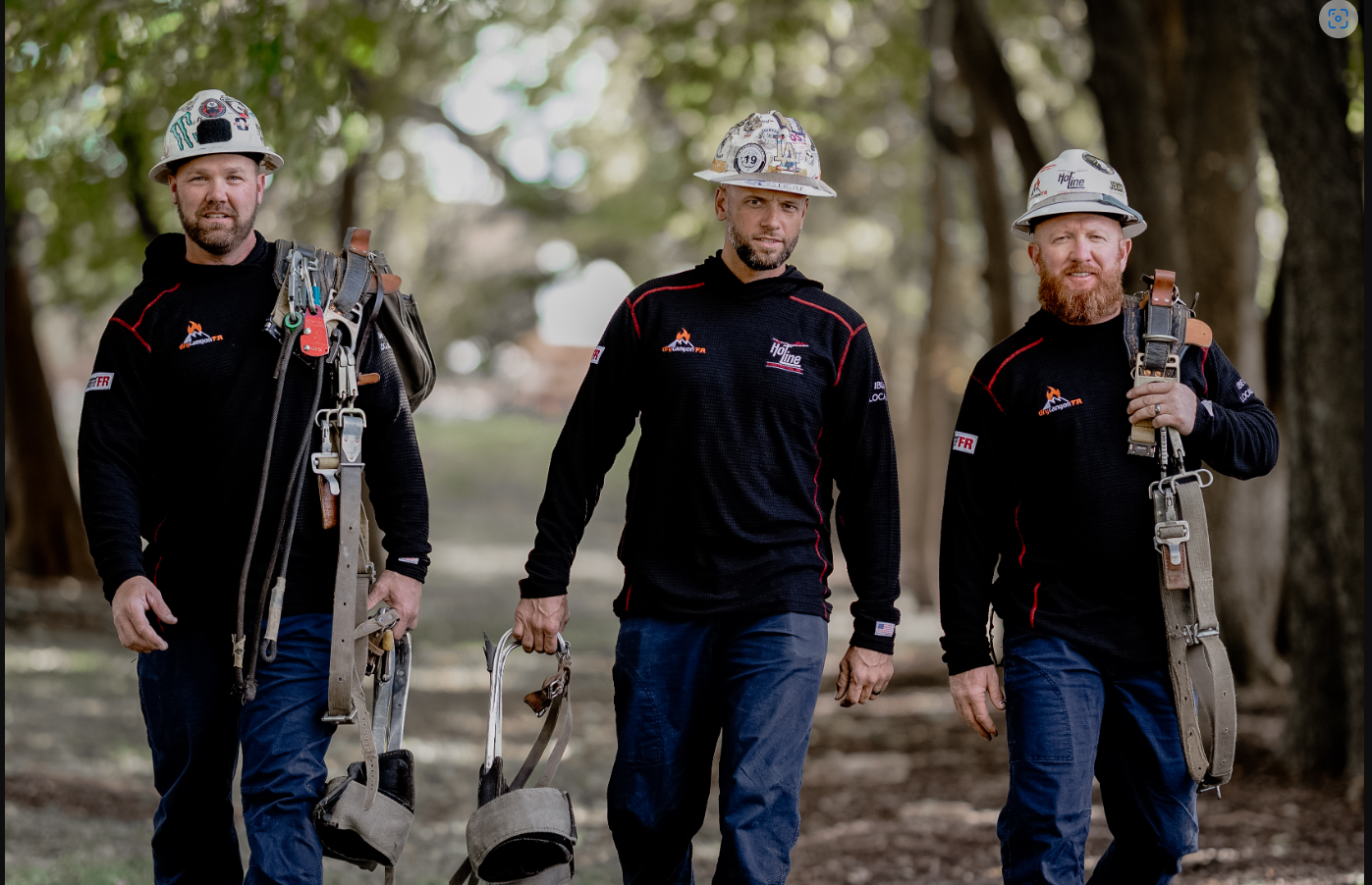 Three workers in safety gear with equipment in park.