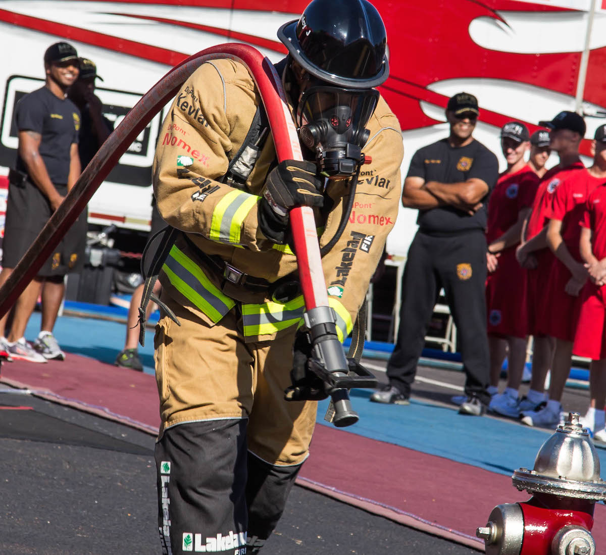 Feuerwehrmann nimmt an der Fire Fighter Challenge teil, Schlauch tragen