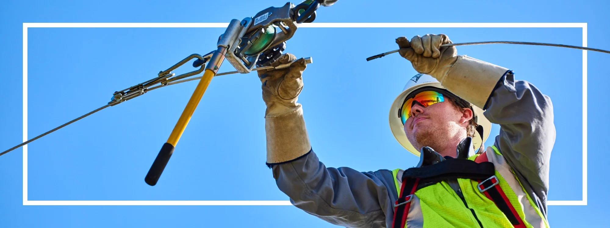 Utility worker donning a Lakeland high visibility vest works on a utility pole