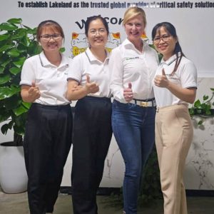 Four people smiling in front of Lakeland Fire+Safety sign.