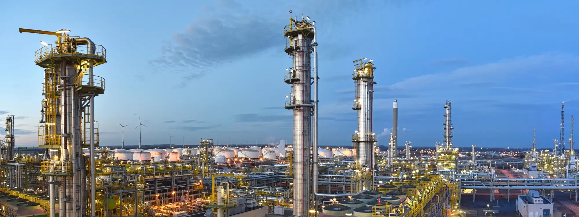 Landscape image of of a large industrial chemical processing plant at sunset