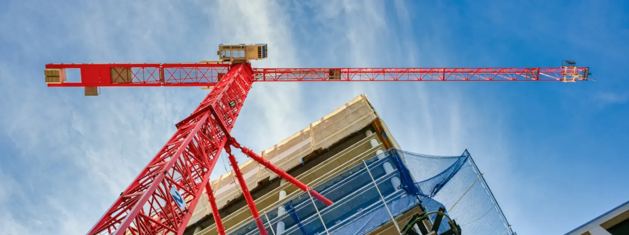 Photo of a large red crane next to a parking deck