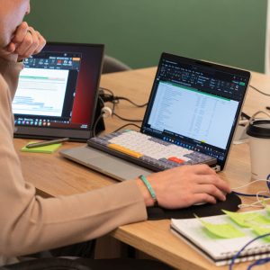 Person working on laptops at desk with notes