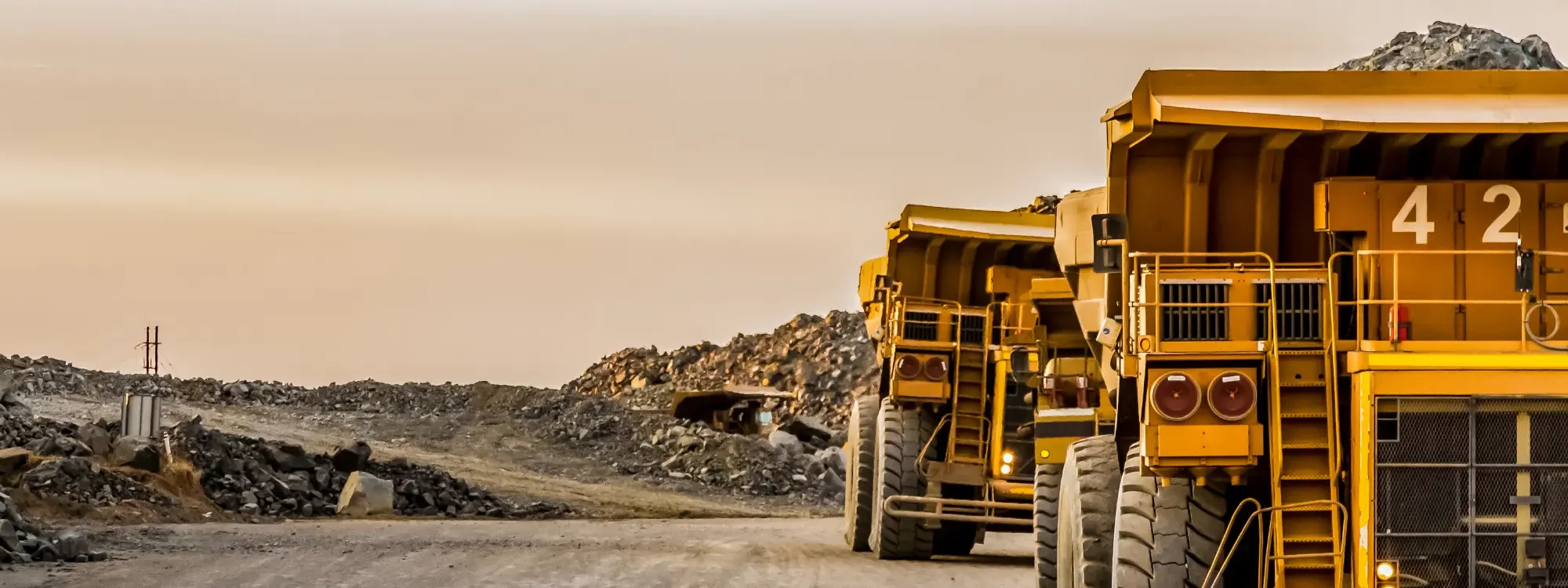 Two mining vehicles driving through a mining site