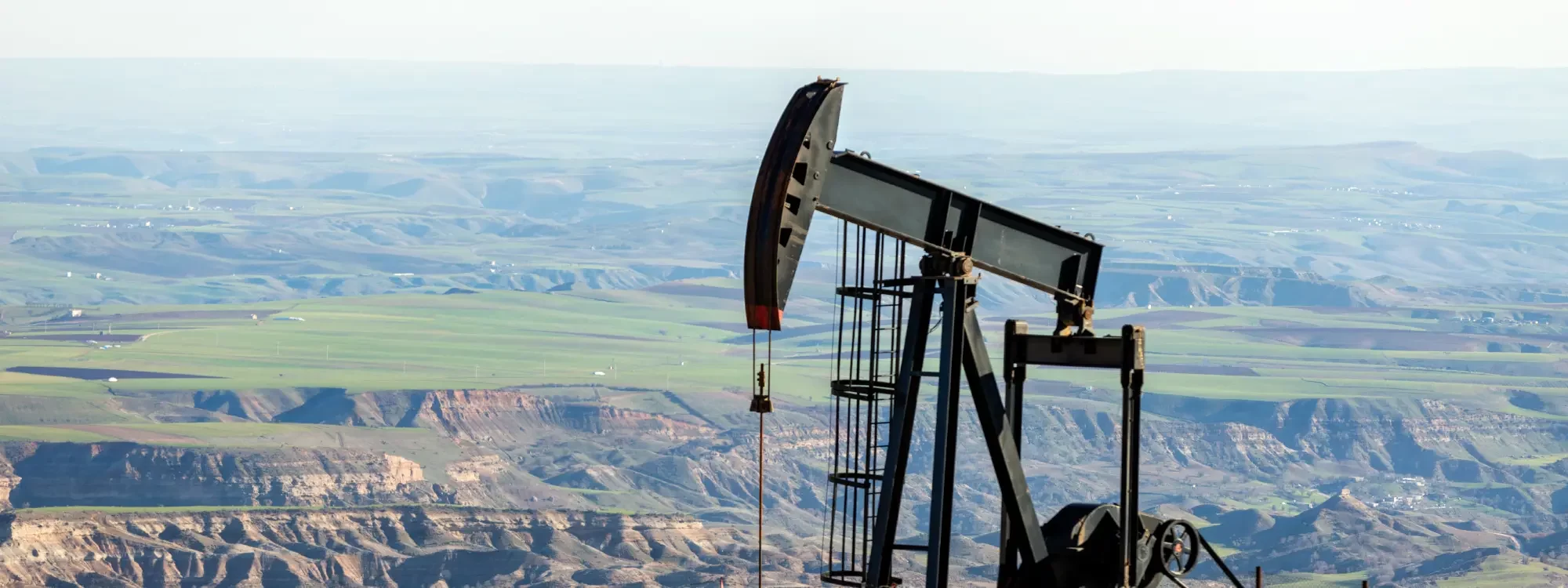 Oil rig standing atop a hill with a deep perspective of valleys and hills lying below in the distance