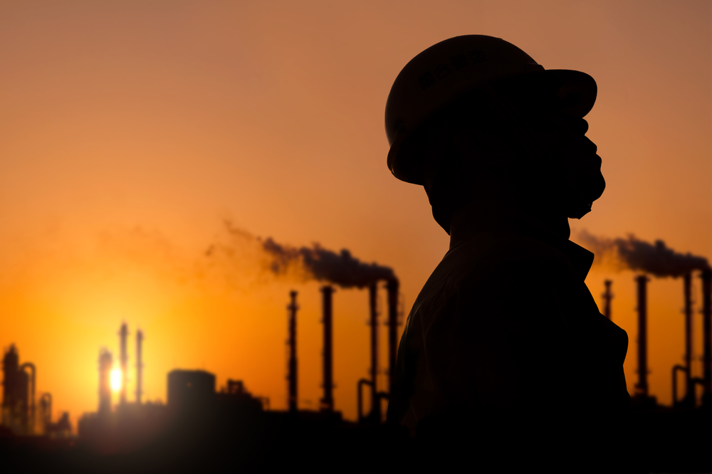 Trabajador industrial en el campo con un amanecer de fondo