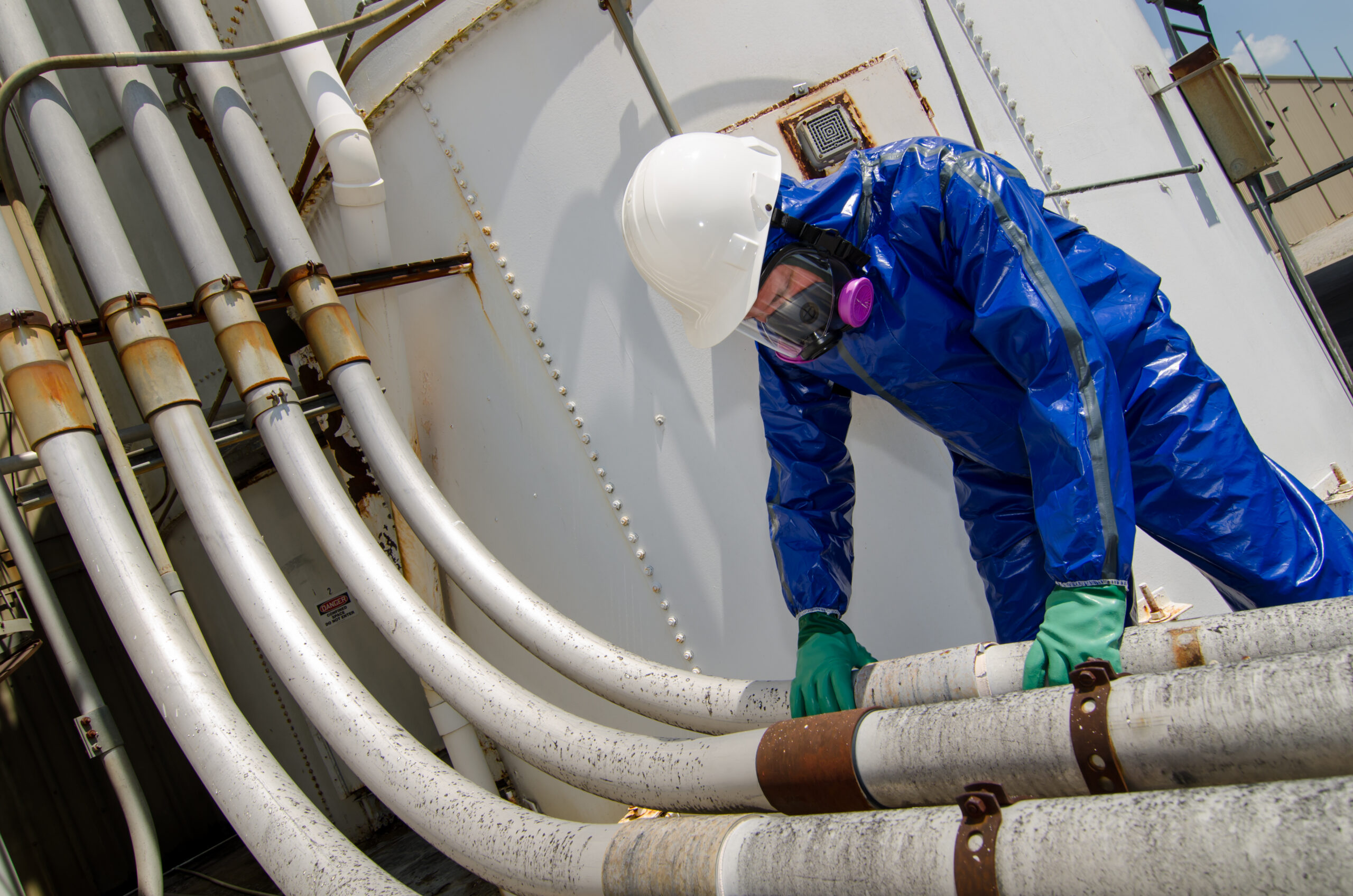 Worker inspecting industrial pipes in safety gear.