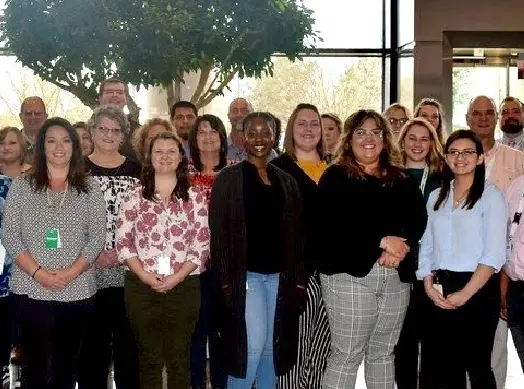 Lakeland Employees standing in front of a tree in the lobby at the Lakeland Industries corporate headquarters