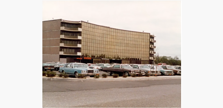 Retro building with parked vintage cars in front.