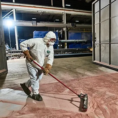 Industrial working sweeping hazardous dust while wearing Lakeland SafeGard SMMS for the utmost protection